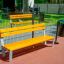 Ryga Bench w/ Backrest դեղին նստարան հենարանով բացօթյա տարածքում: