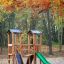 Mini Play Modern Nature playhouse with slide՝ փայտե խաղային համալիր հարթակով և սլալով, շրջապատված աշ