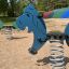 Երեխաների խաղահրապարակում կանգնած է Pony rocking՝ կապույտ ձիաձև շարժվող լավարանով։